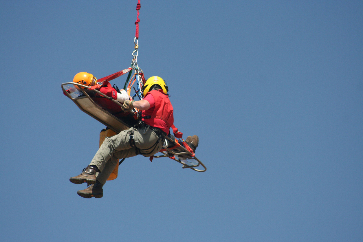 Rescue worker airlifting civilian in disaster.